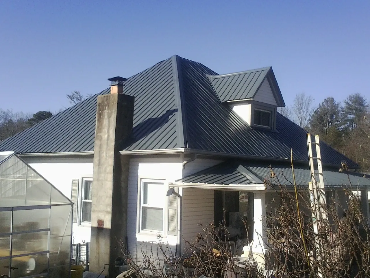 Dark blue standing seam metal roof on a white farmhouse with dormer — Slate & Tile Roof Repair by Roofing Brothers in El Reno