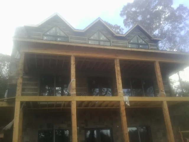 Dormers and porch framing on a large log home under construction — Roof Coating work by our crew in El Reno