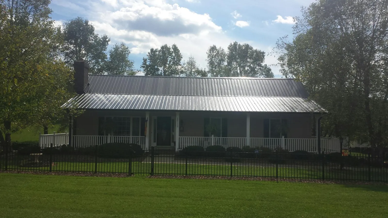 Gray metal roof on a brick ranch with a full width front porch — Gutter Guard Installation work by our crew in El Reno