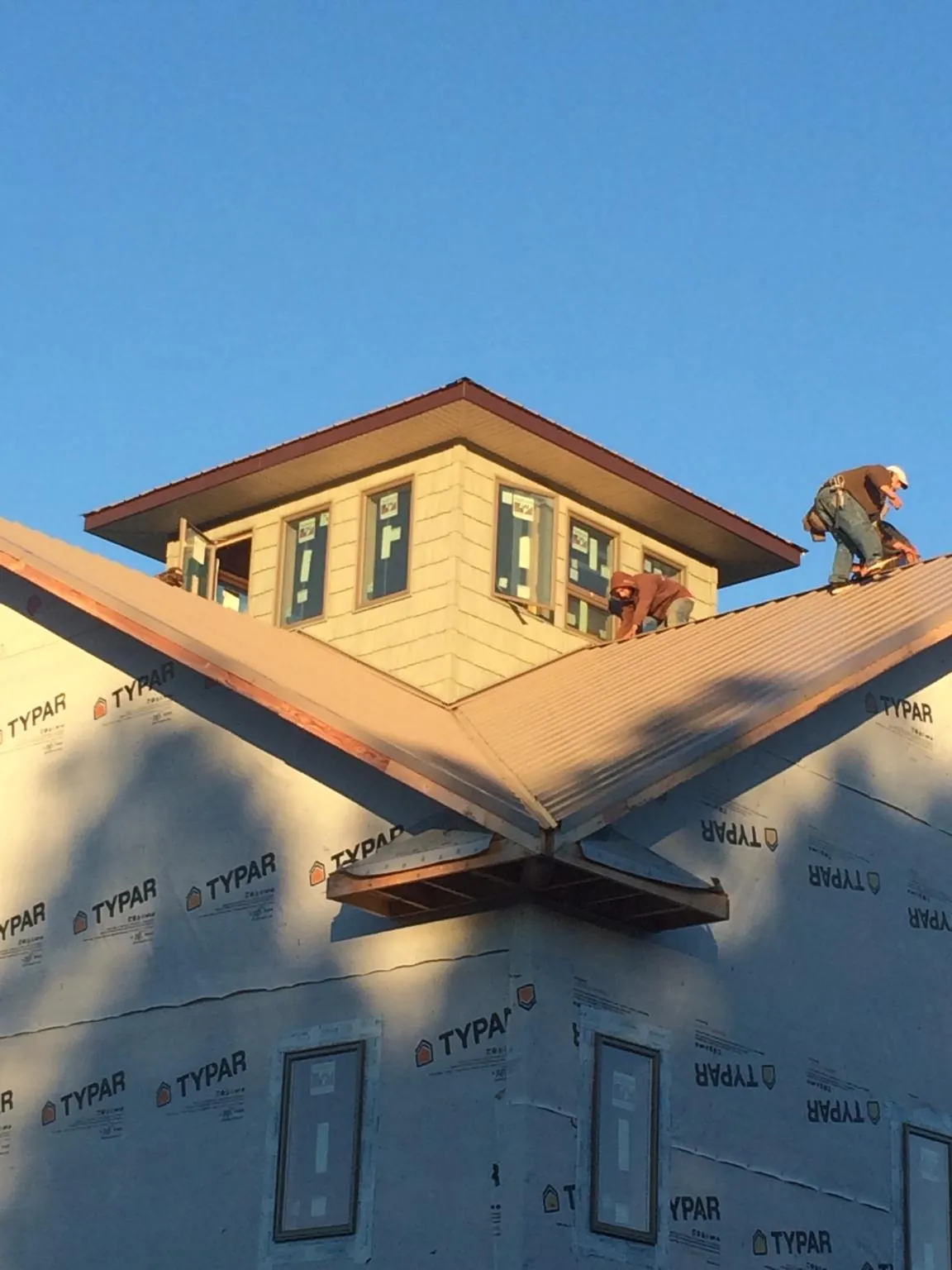 Roofers working around a rooftop cupola on a new metal roof at sunset — Roof Waterproofing in El Reno by Roofing Brothers